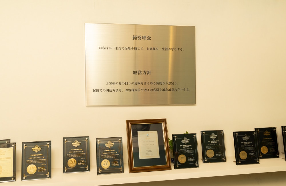 壁に飾られた経営理念・経営方針と数多くの表彰楯